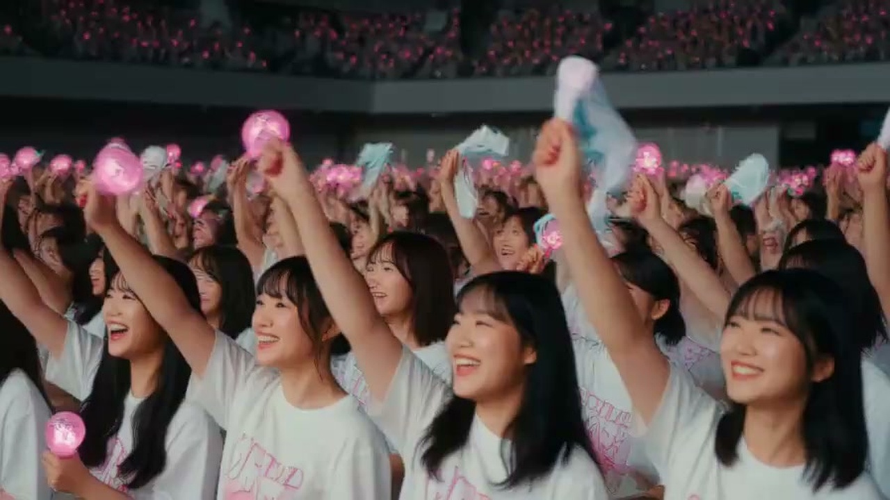 満員のライブ会場でペンライトを掲げて歓喜するアイドルファンのスナップ